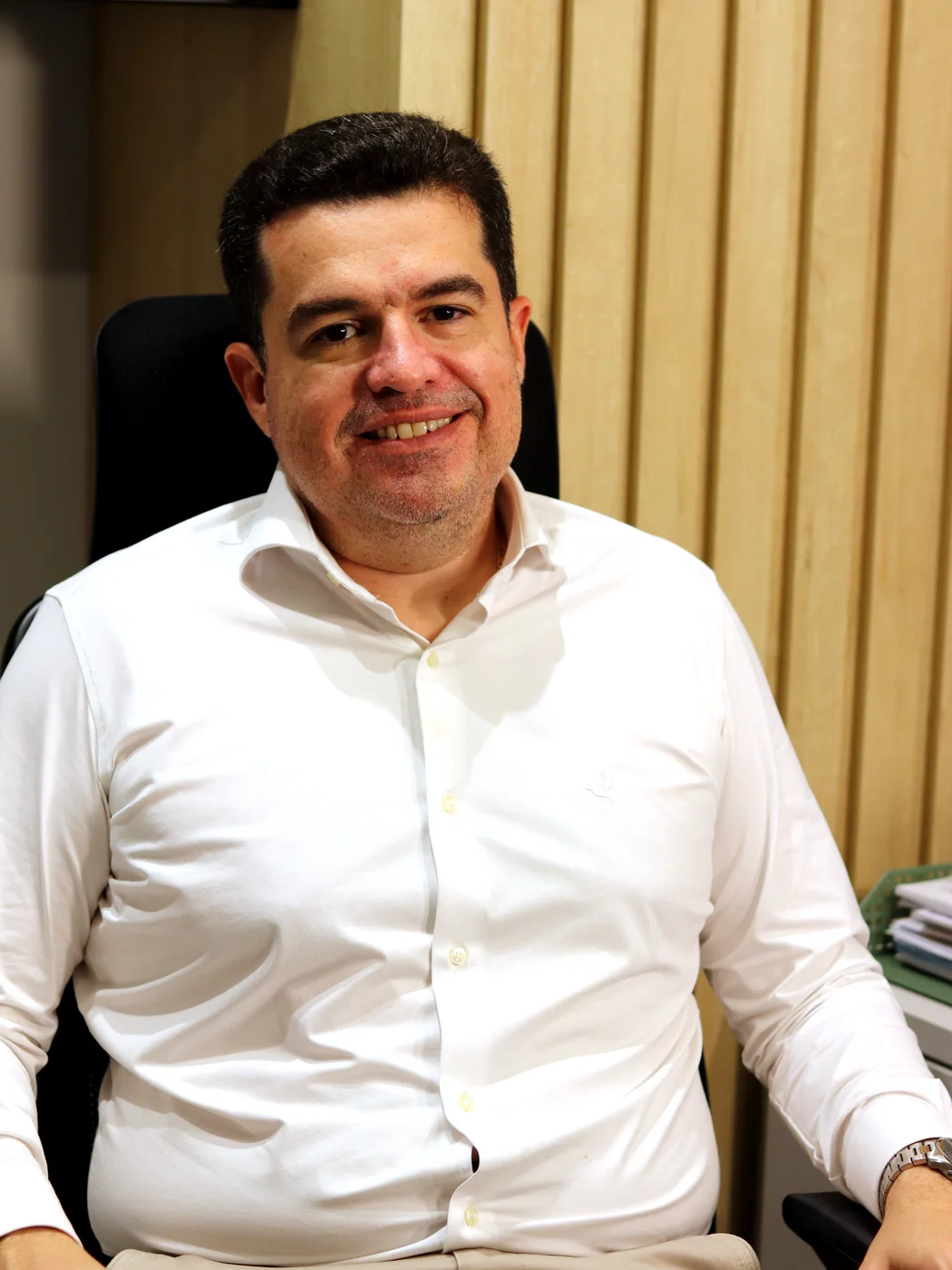 Dr. Rodrigo Domingues sorrindo, sentado em seu consultório